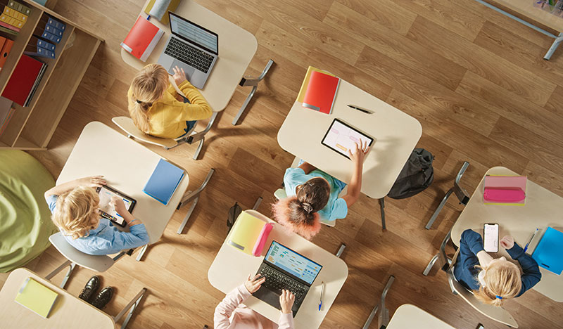 Kids using tablets, computers, and smartphones in a classroom